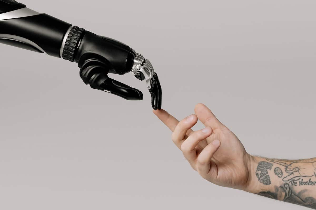 Bionic hand touching fingers with a human hand.