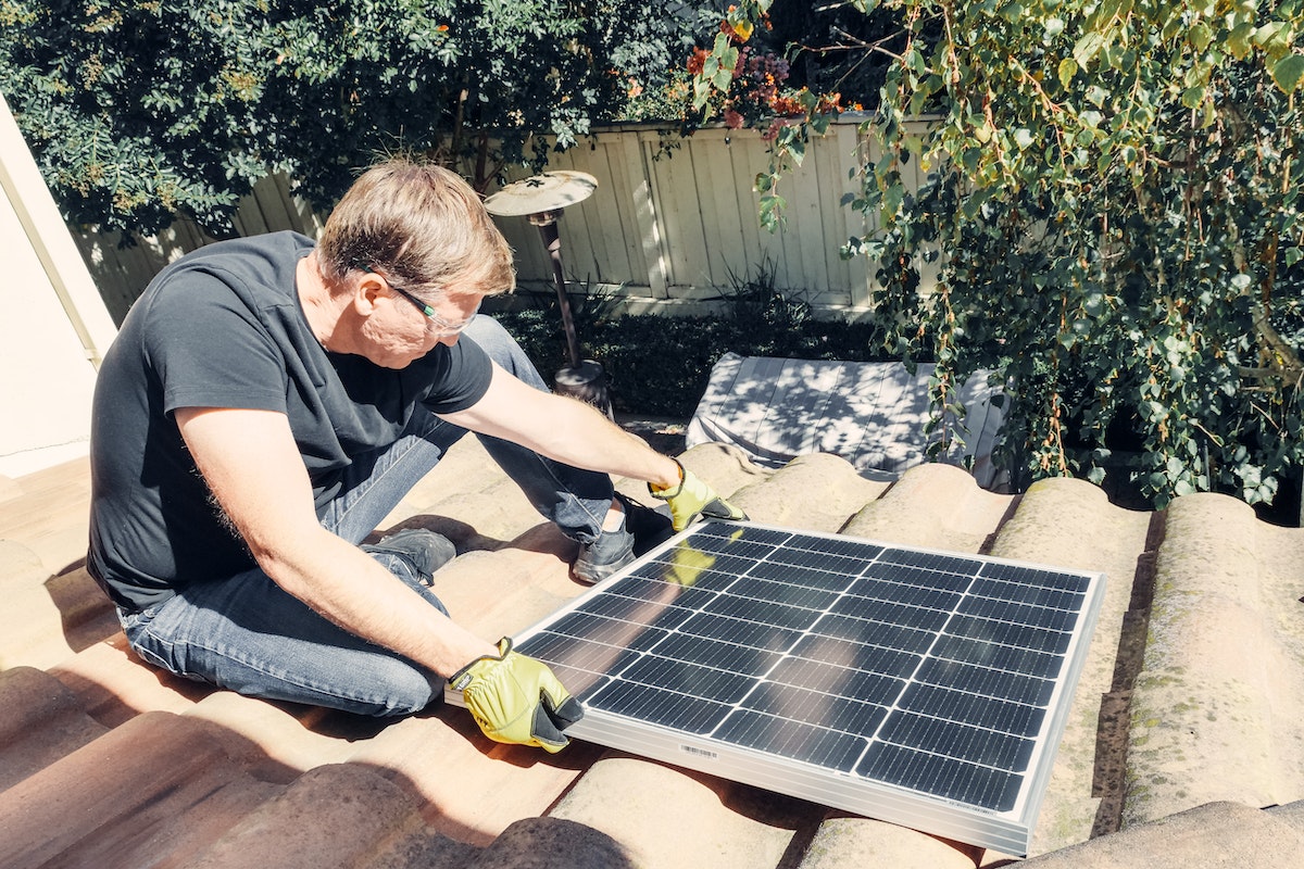 Man installing solar panel on a house roof.