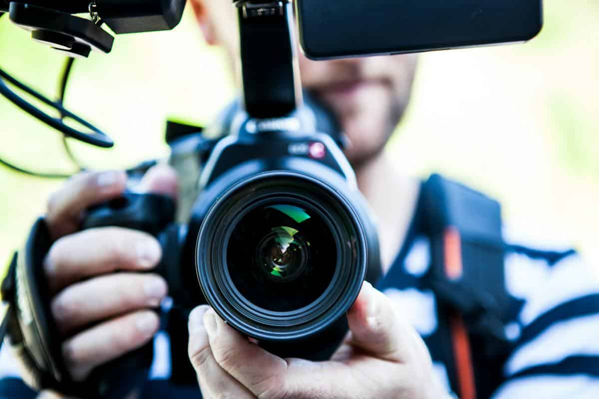 Man holding camera as he shoots a video to be used in social media marketing.