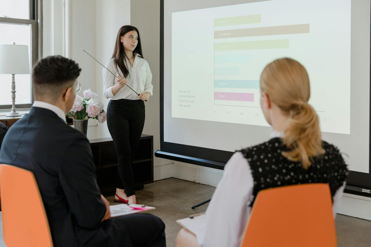 Woman in White Long Sleeve Shirt Standing Near Projector Screen