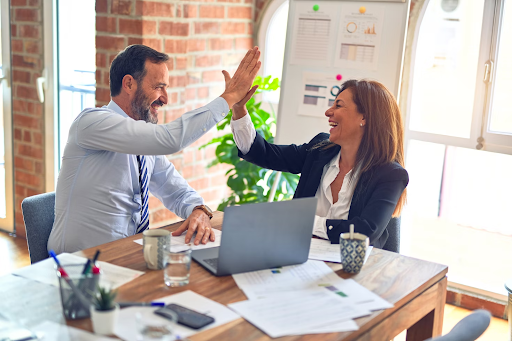 woman and man in a office celebrating a project win